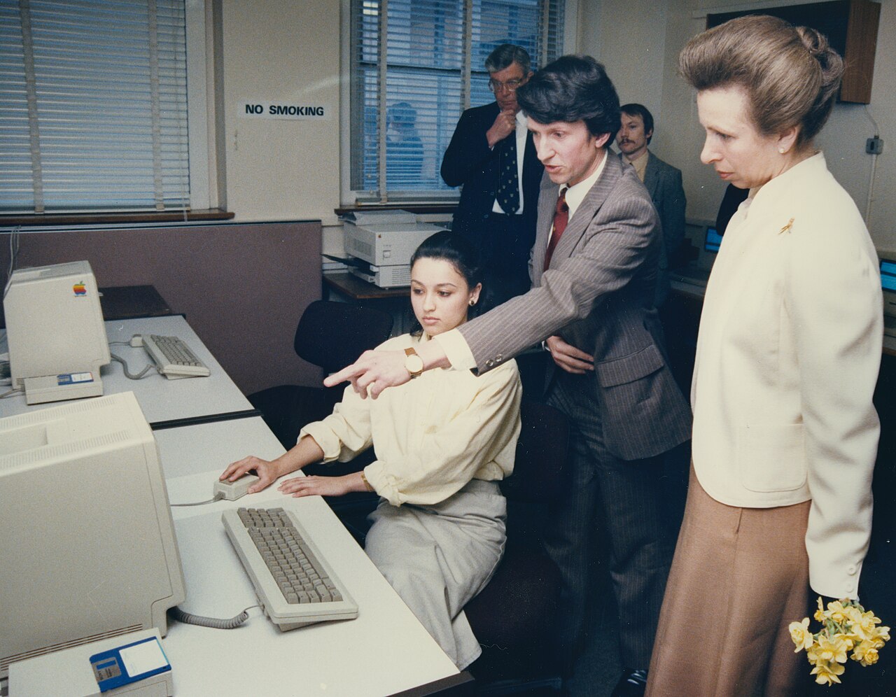 Homme pointant son doigt vers un ordinateur. Il est accompagné de la princesse Anne.